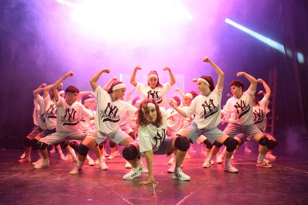 A dance crew mid-routine under purple stage lights